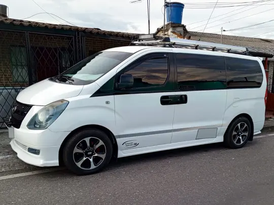Van Hyundai H-1 blanca con portaequipajes, vista de frente y de lado
